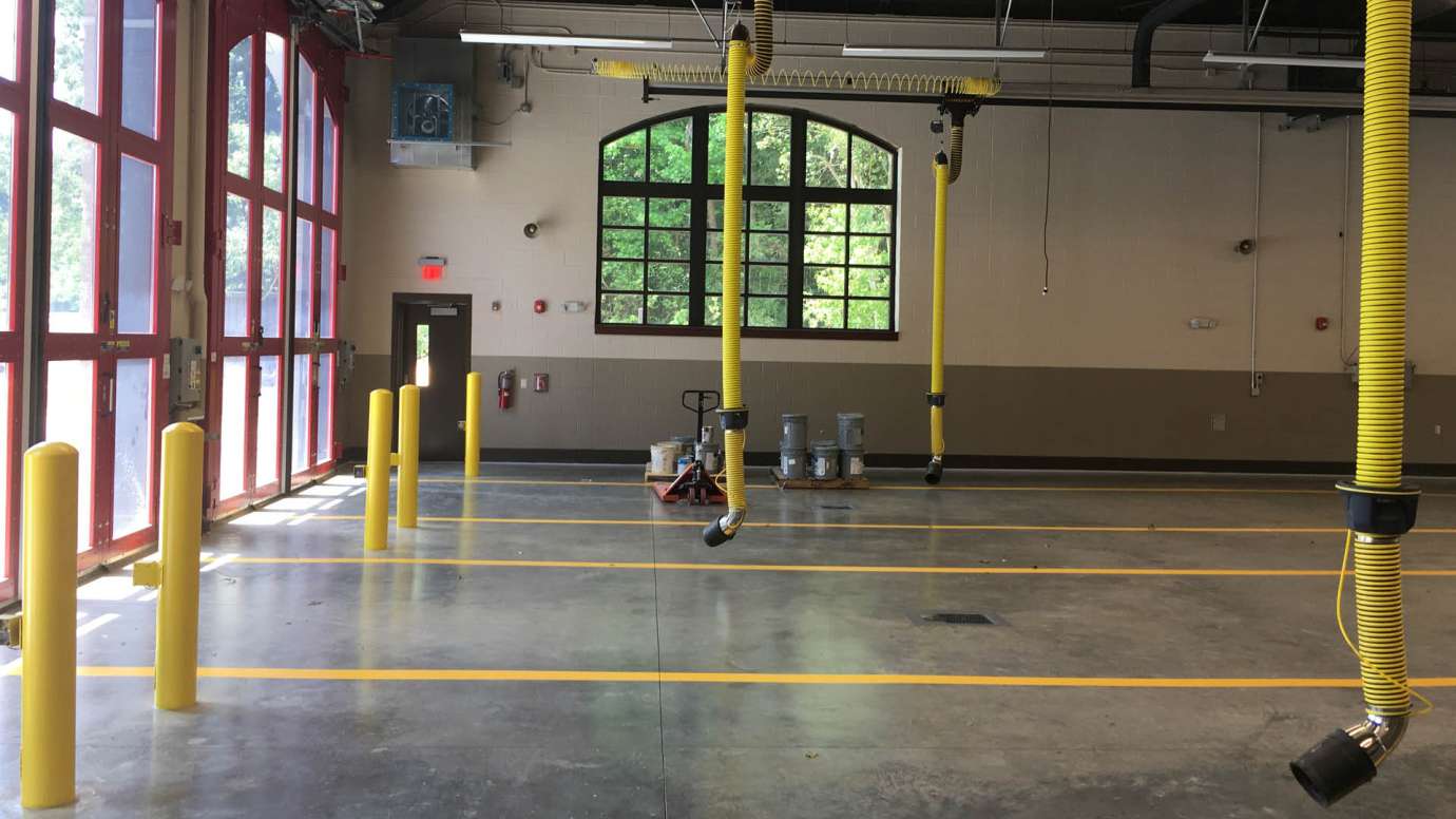 The new bay at Fire Station 14 that has red, rounded doors, yellow lines for parking trucks, and concrete floor. 