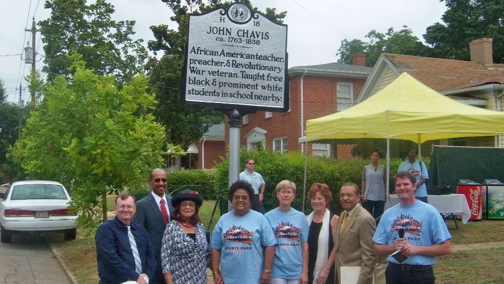 Group of people smiling beside Historical marker sign for John Chavis