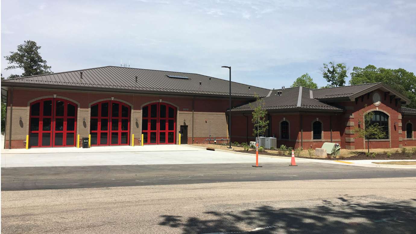 A view of the new fire station 14, which has three red, rounded bay doors and a brick exterior. 