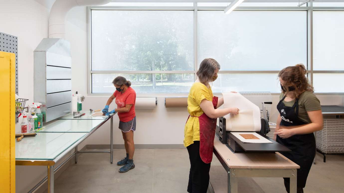 People work with the press in the Bookmaking & Printmaking Studio in Pullen Arts Center
