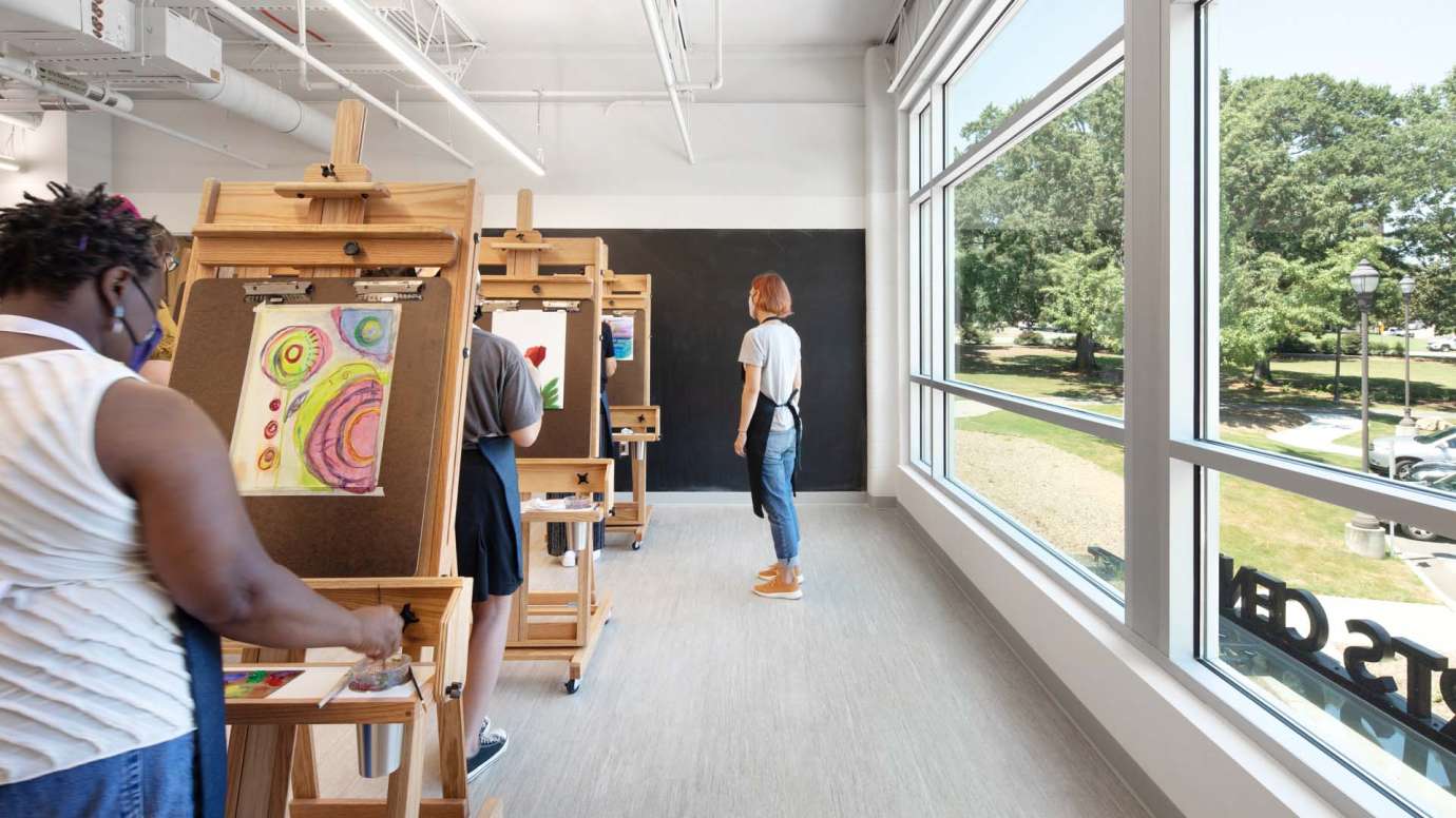 An instructor oversees students painting on easels at Pullen Arts Center