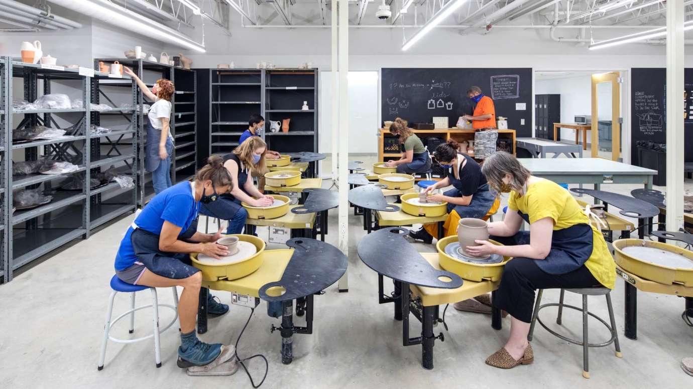 People sit and create at pottery wheels in Pullen Arts Center