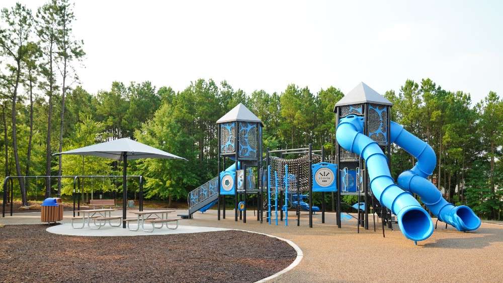 Playground structure with large blue slides and covered picnic tables