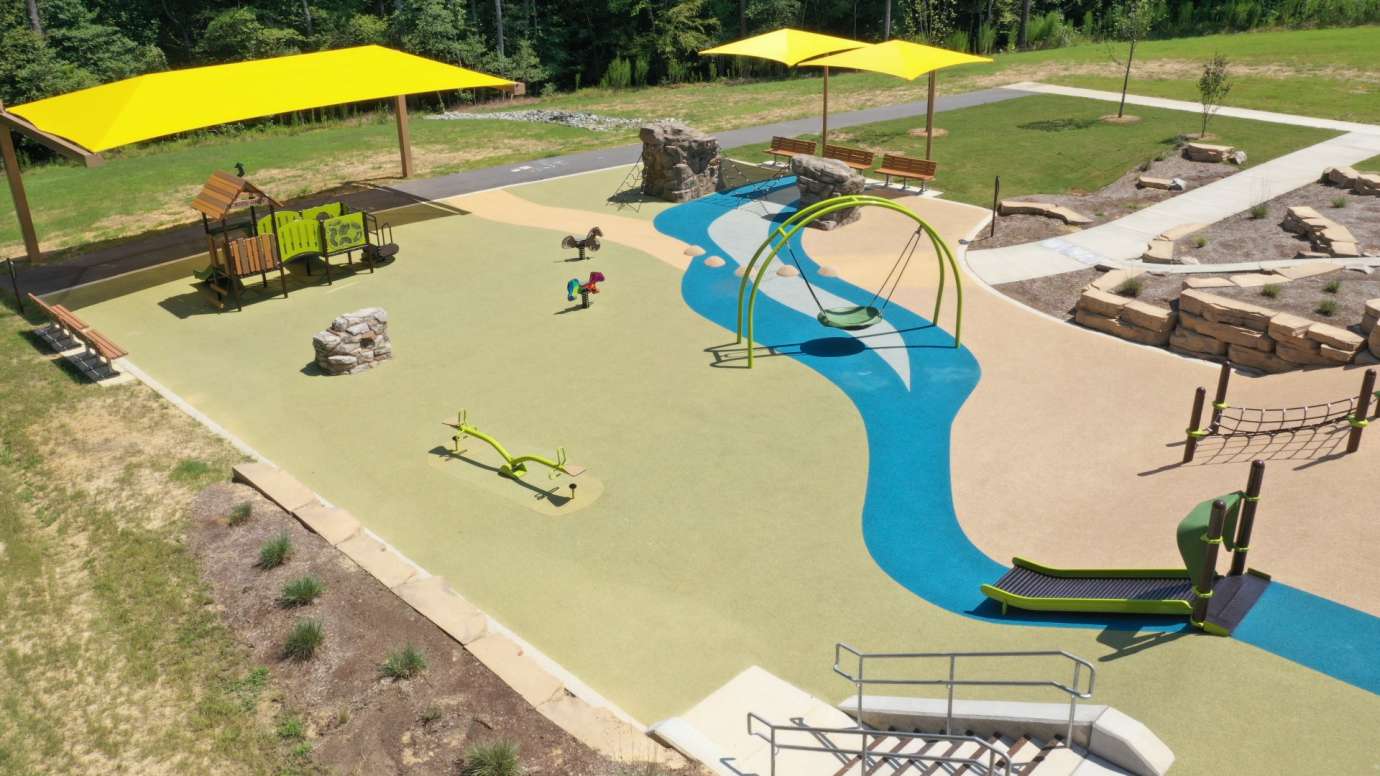 Aerial shot of the River Bend Park playground with yellow shades and rubber surface and play structures