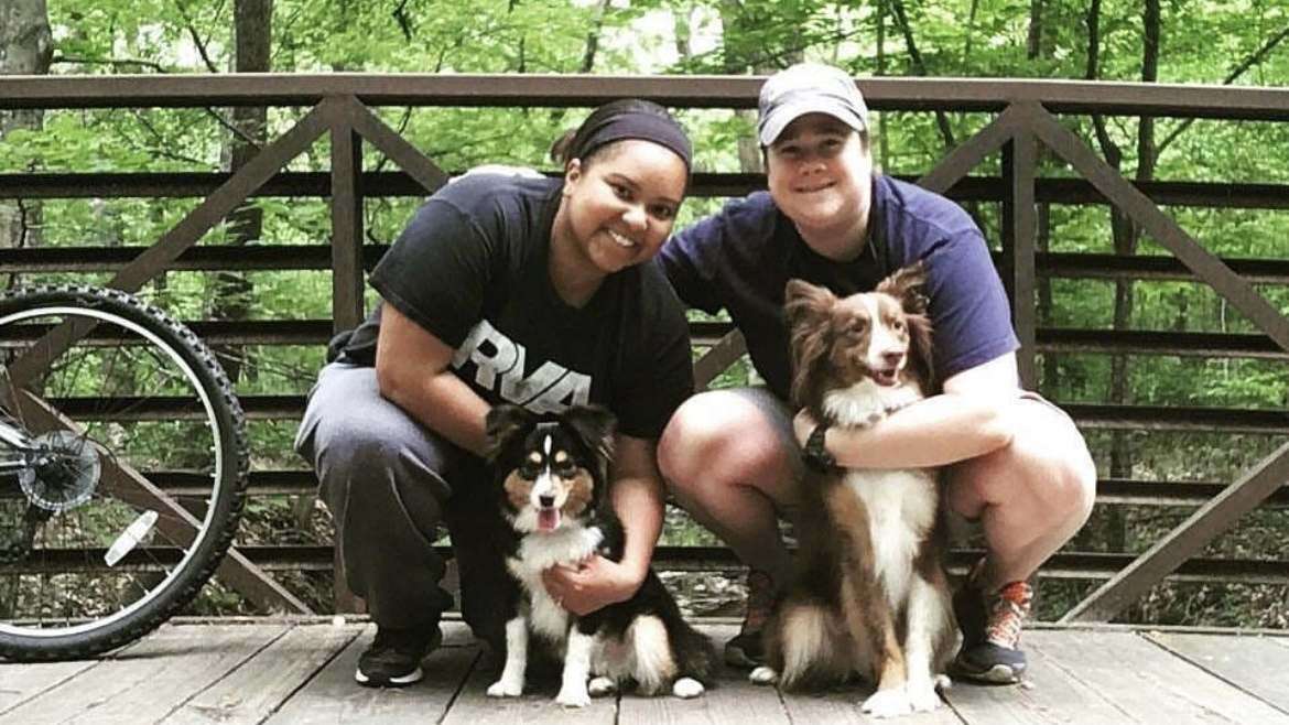 Two women on bridge smile with dogs