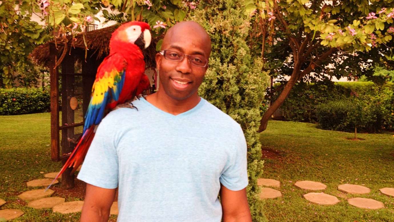 Man smiling with parrot on shoulder