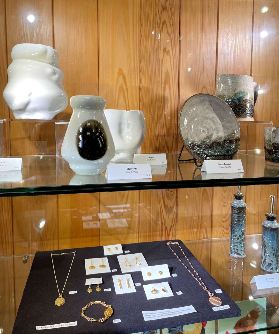 A display case filled with handmade pottery and jewelry pieces