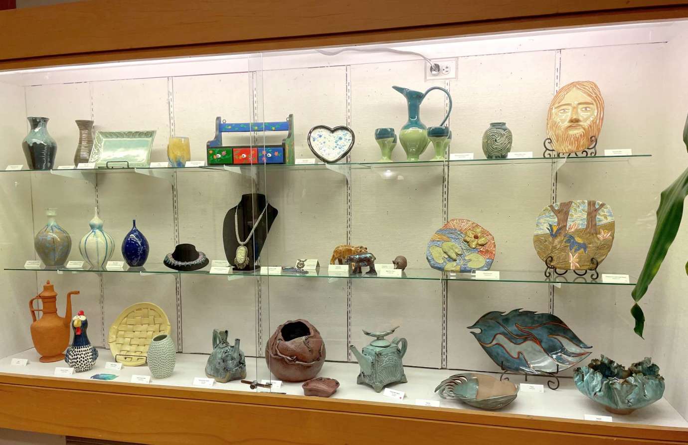 A display case filled with handmade pottery and jewelry pieces