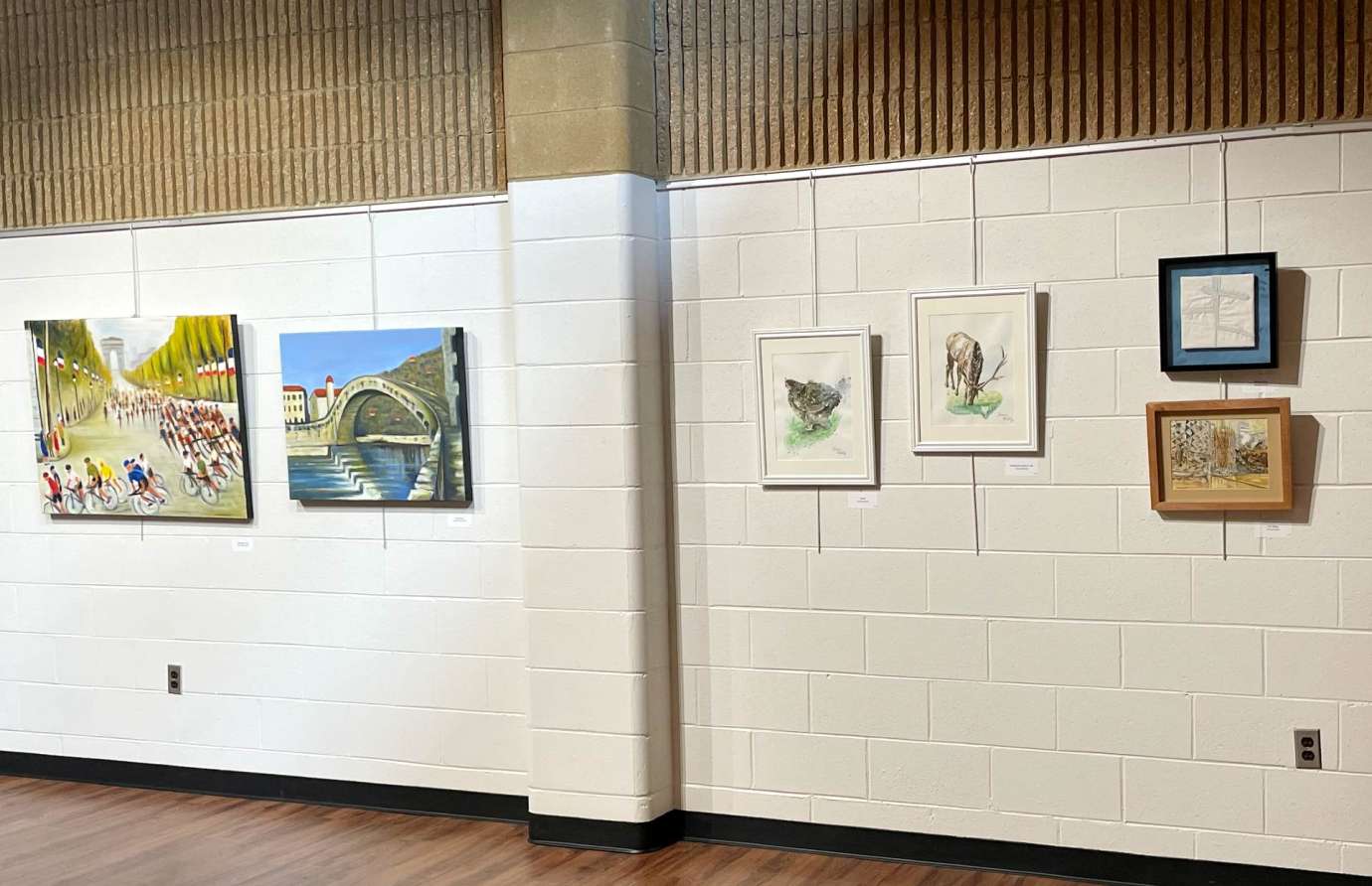 Artwork of varying mediums, sizes, and subject matters hanging on gallery wall 