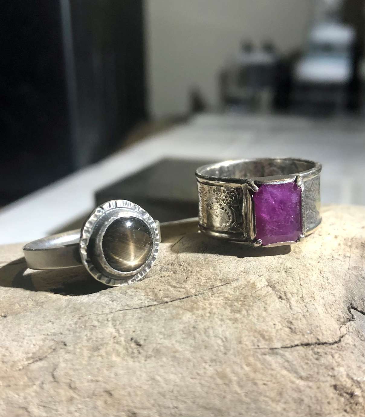 Two rings, a smaller one with a beige-green circle stone, a larger one with a square magenta stone