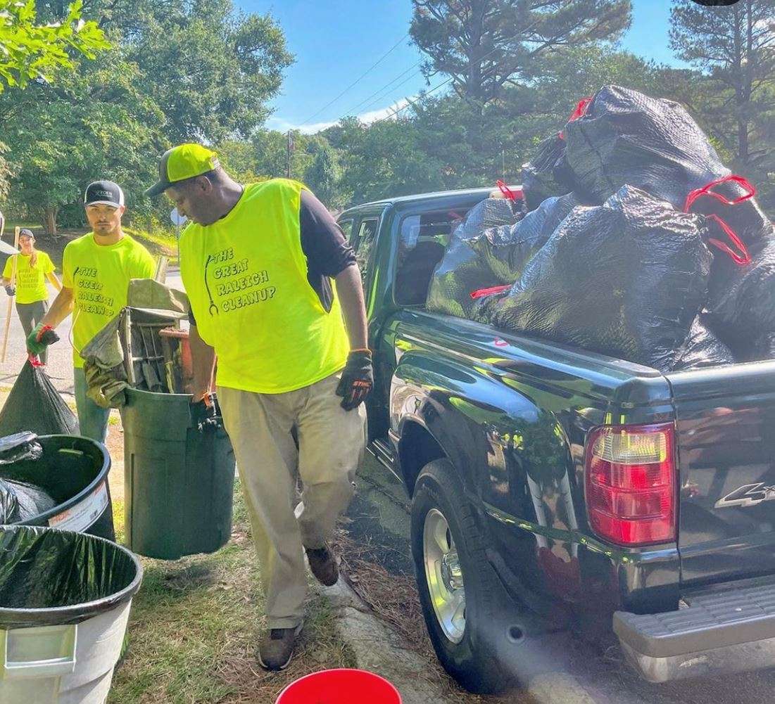 People loading trash into a pickup truck during community cleanup event