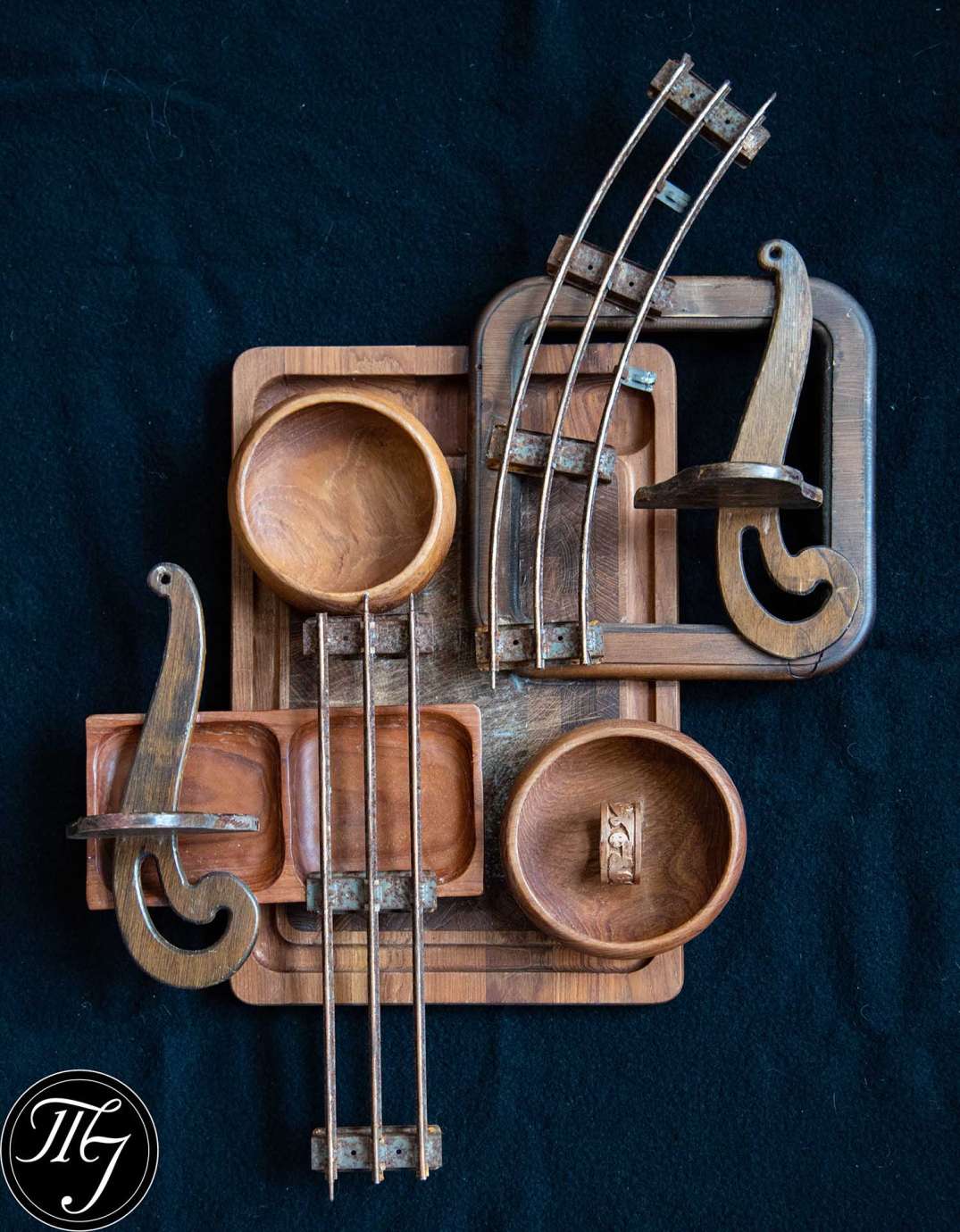 A wood sculpture made out of different shapes made from metal and wood; some resemble wood bowls and pieces of musical instruments