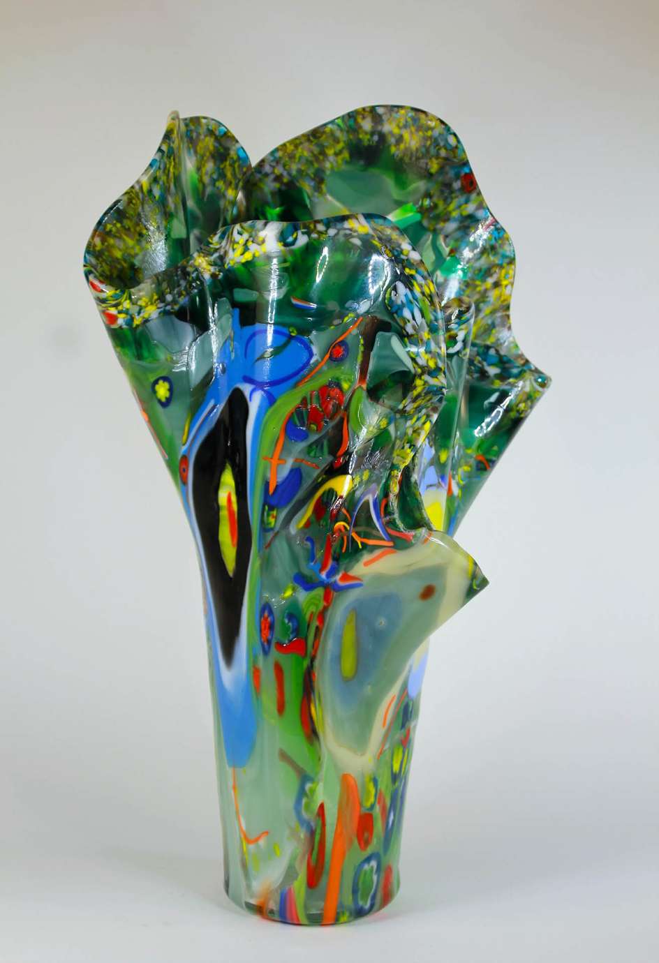 a multi colored blue, green, yellow, and red glass vase with many folds