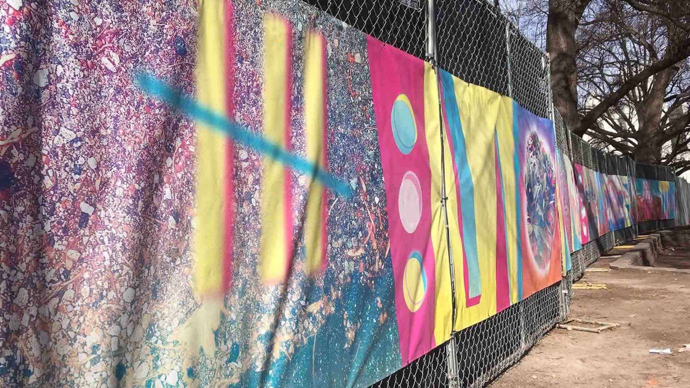 a colorful banner made of abstract lines and shapes covers a construction fence