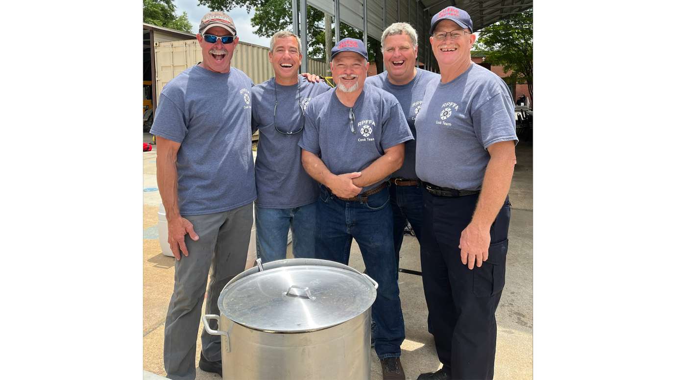 Raleigh Fire Department chefs posing by pot of food they cooked for retirement luncheon