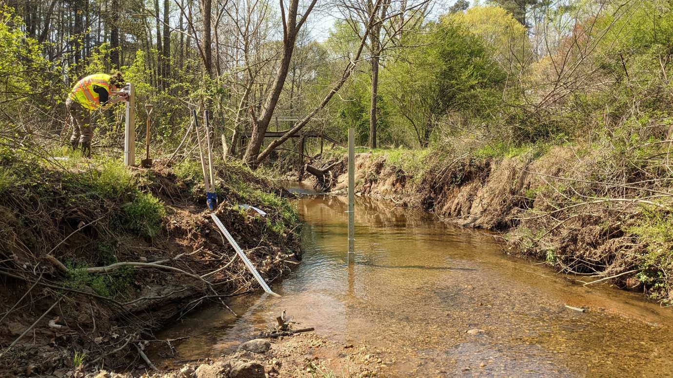 Staff measuring stream water flow