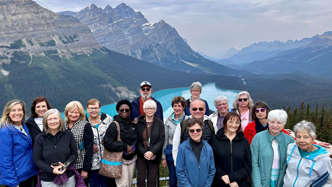 a group of active adults standing in front of mountains