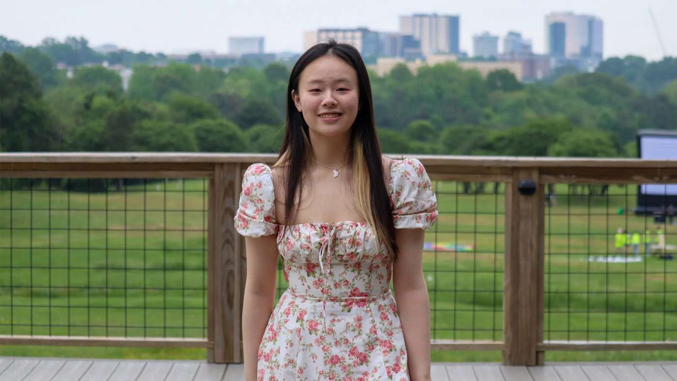 Lisa Wang poses in front of Raleigh skyline