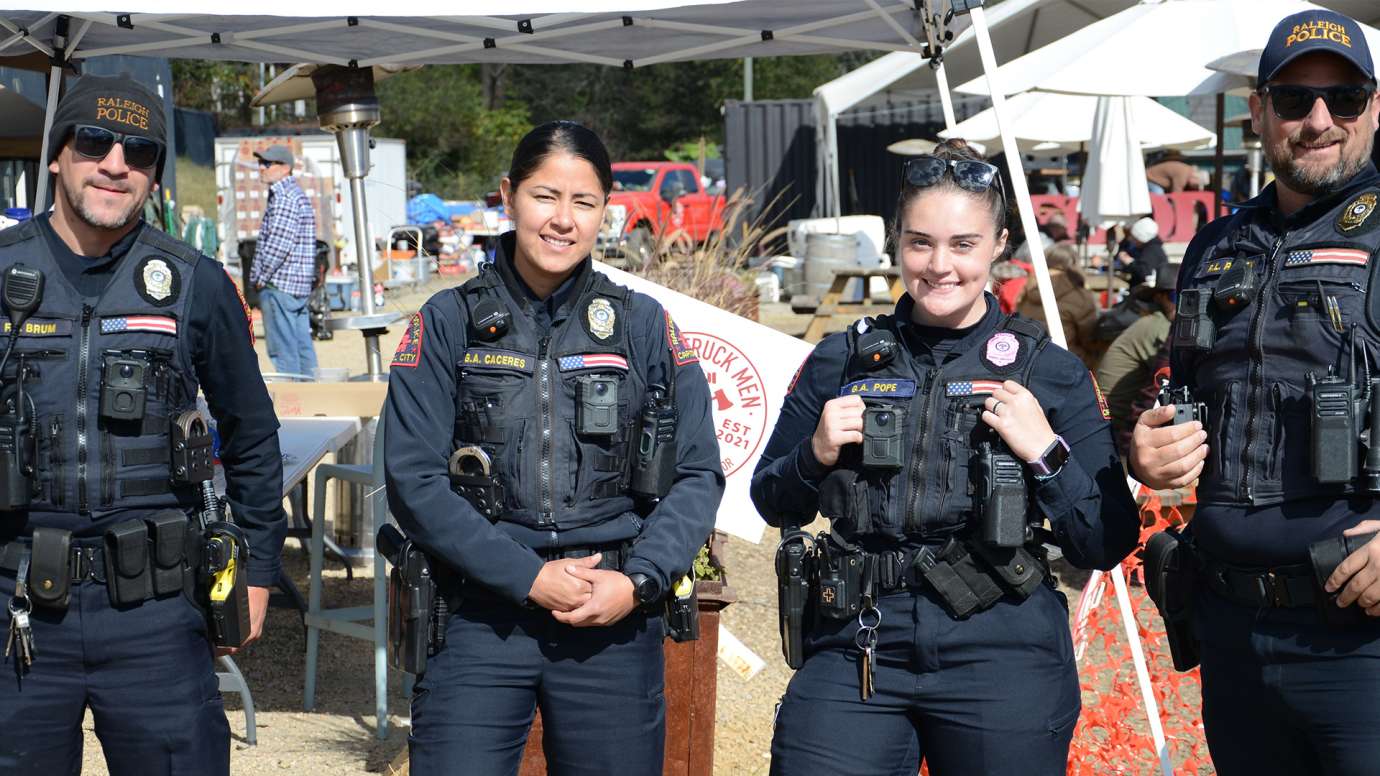 Two female and two male officers pose for photo with tents and support in background.