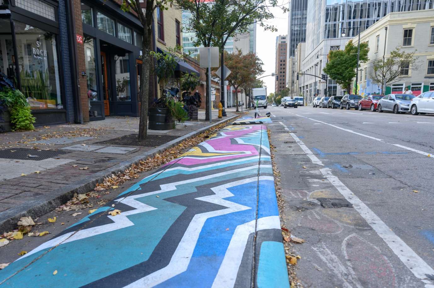 Brightly colored geographic mural painted on raised concrete in a downtown city street. 