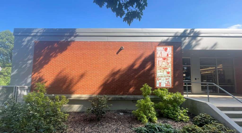 Brick exterior wall at pullen arts center with a vertical mural with tools. 