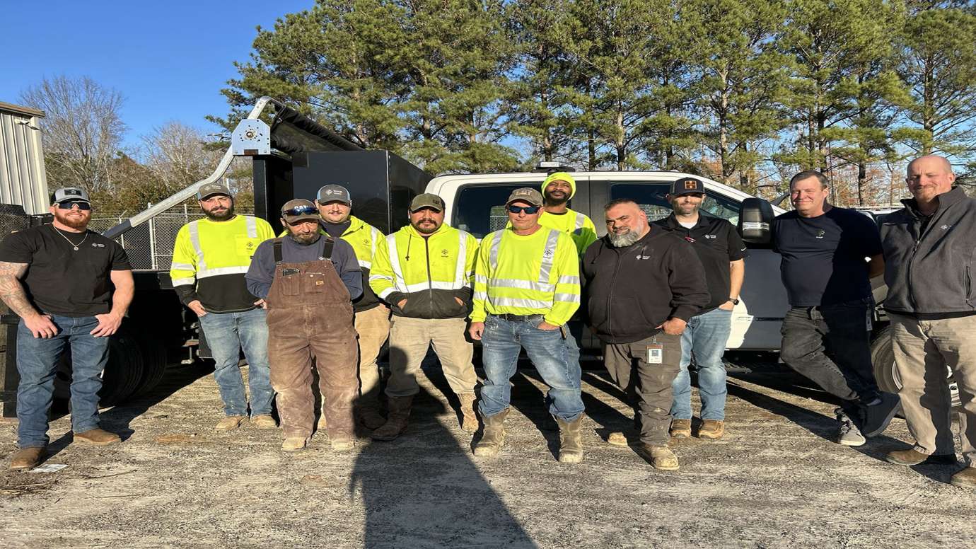 a group of men in public utility gear standing in front of a truck