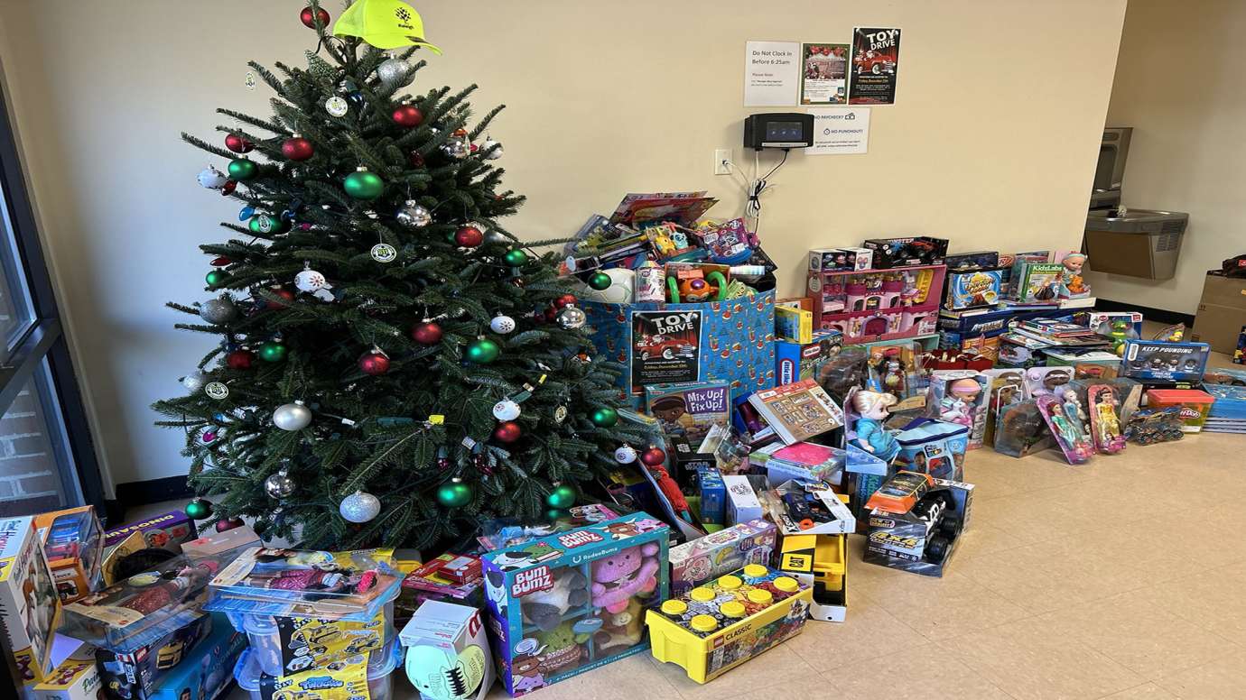 Lots of toys near a Christmas tree in an office lobby.