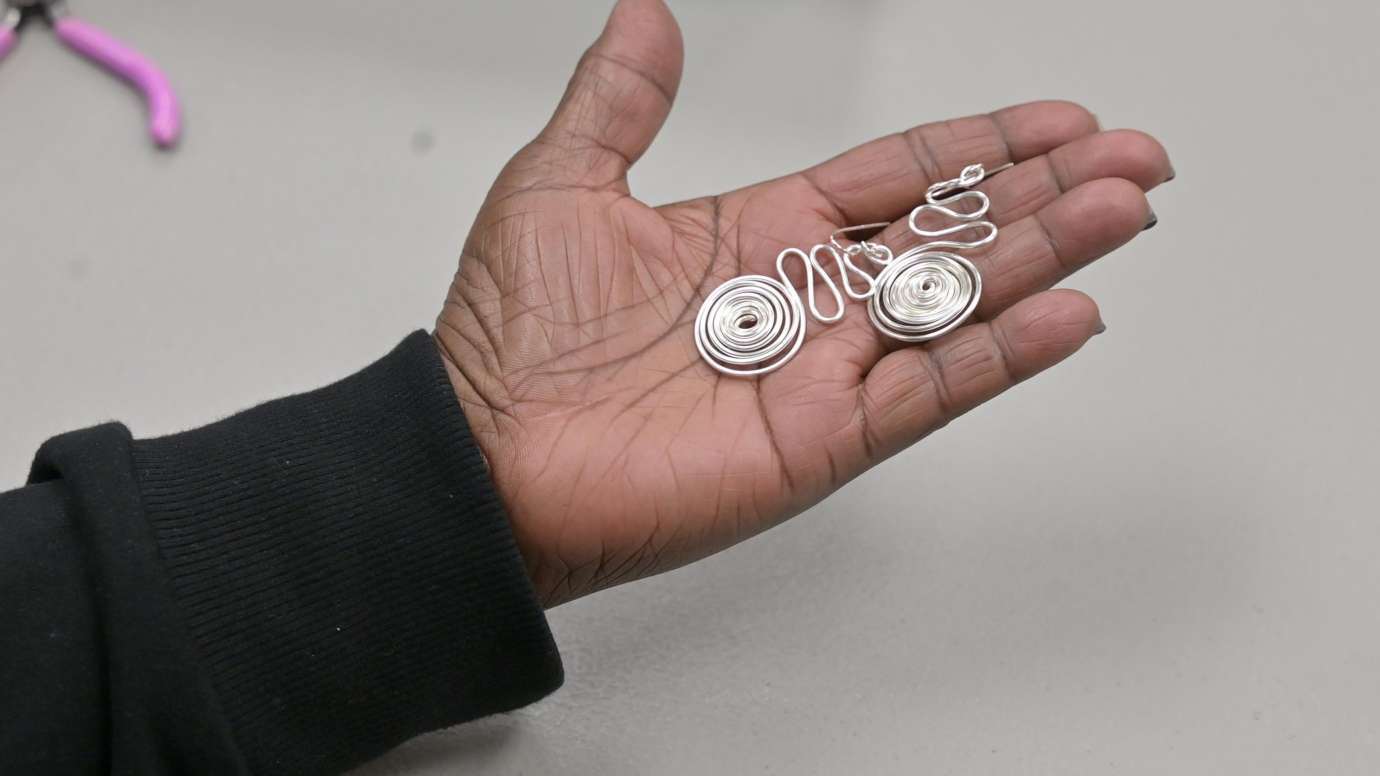 an image of a hand holding hand-made earrings