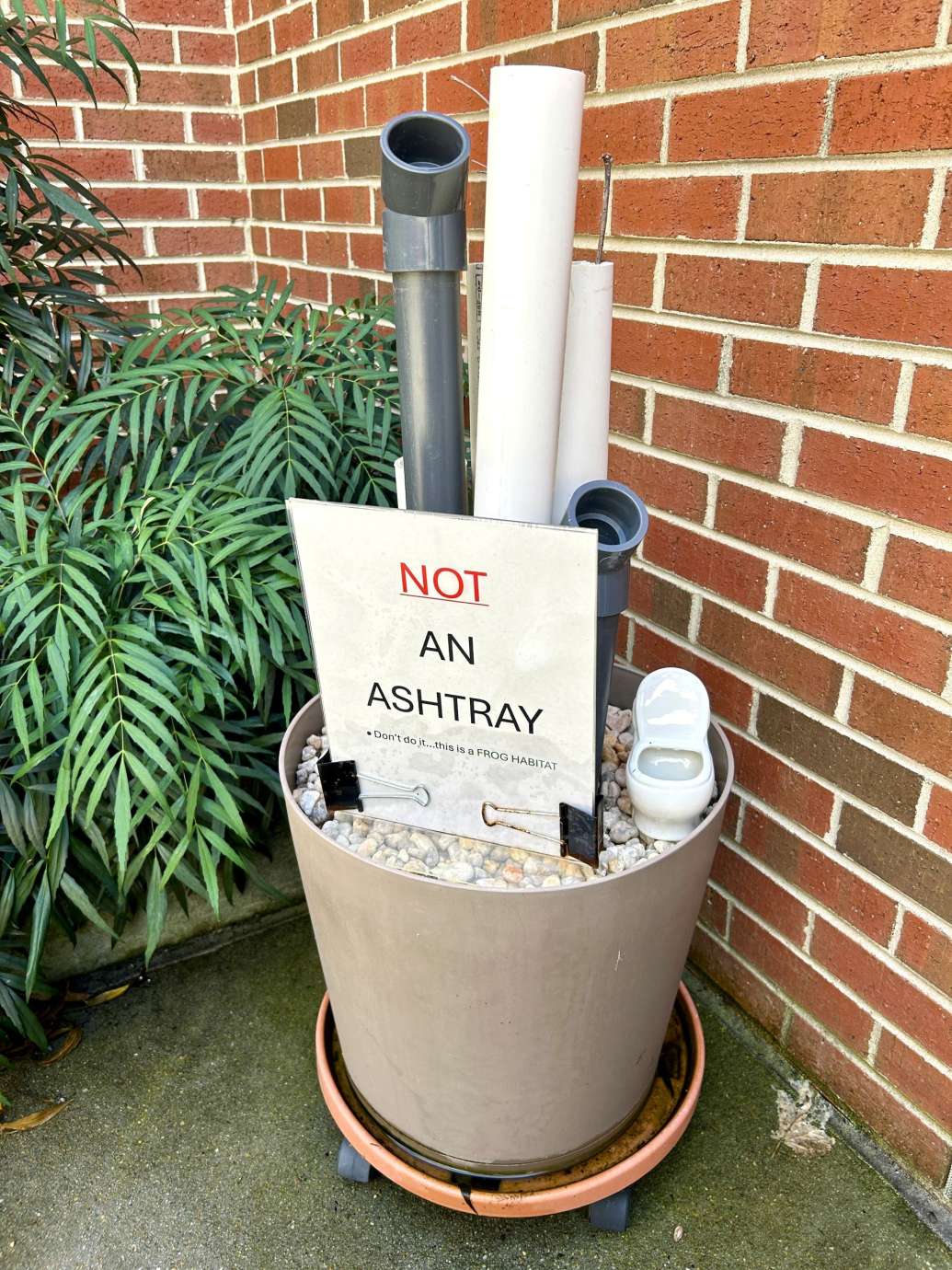 Planter filled with rocks with tall plastic pipes standing up 