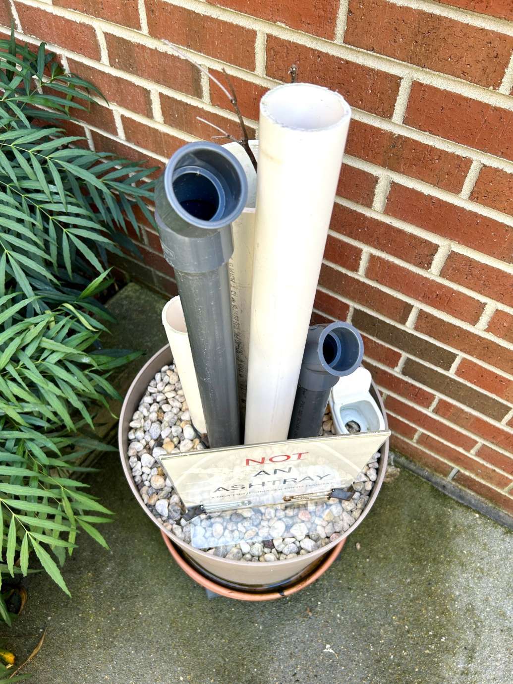 Planter filled with rocks with tall plastic pipes standing up 