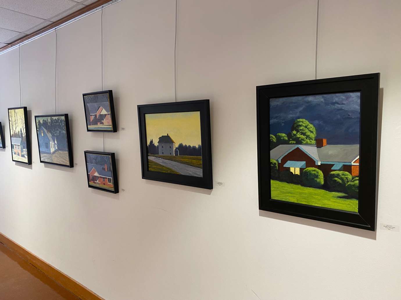 Oil paintings of houses hanging on a white wall 