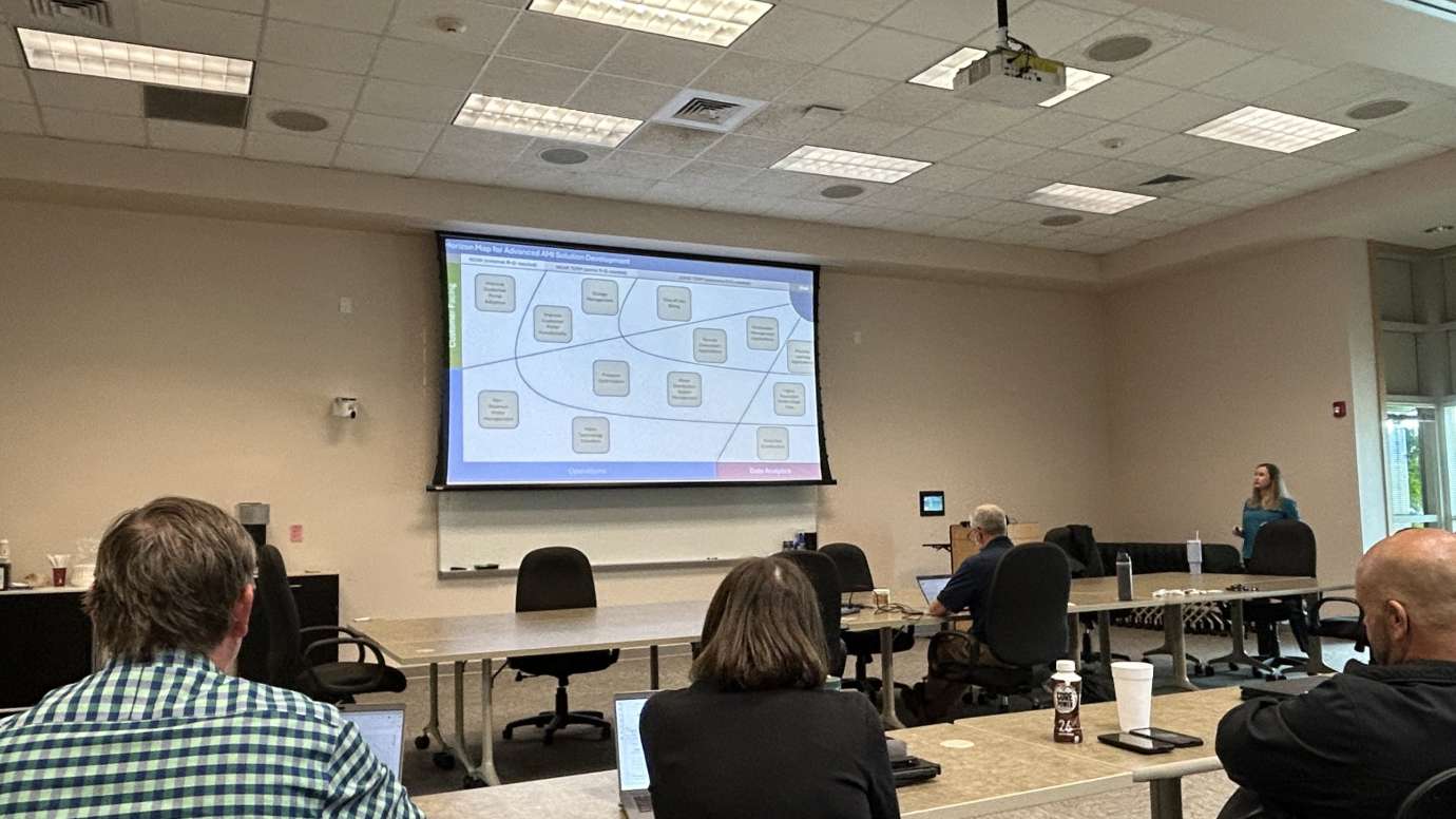 Workers sitting at a desk watching a powerpoint presentation