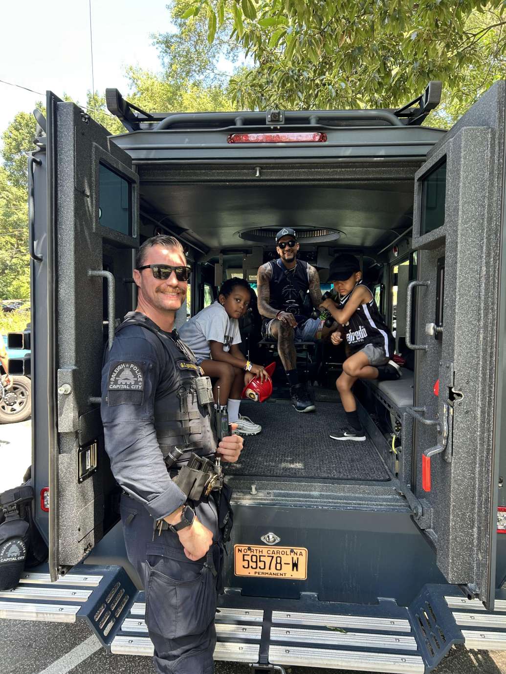 NBA player, John Wall, and community members sitting in police truck