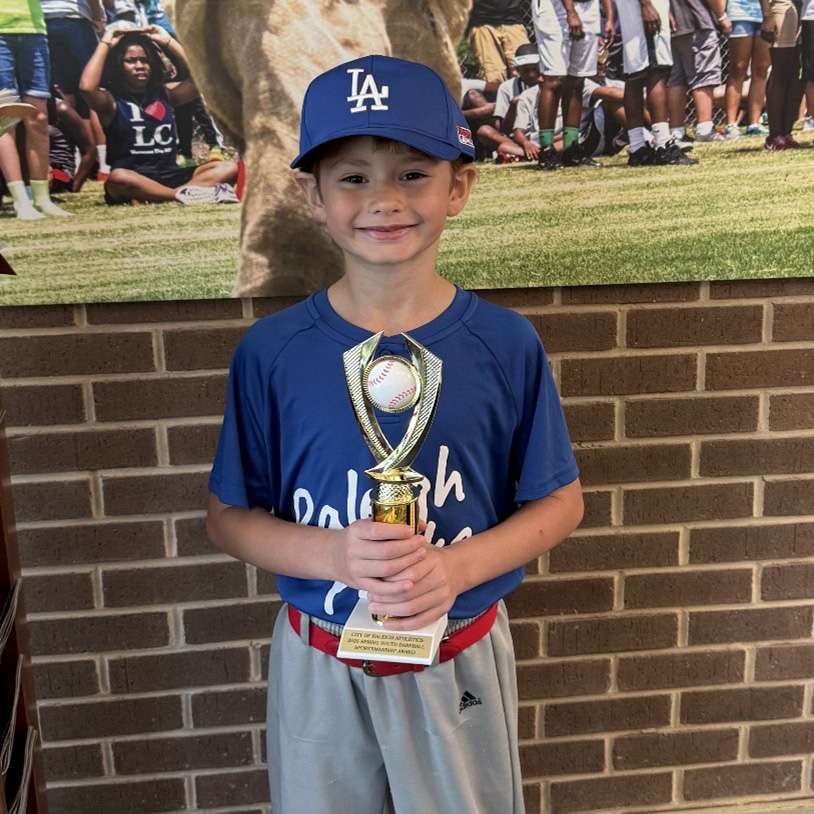 a young baseball player holding an award 