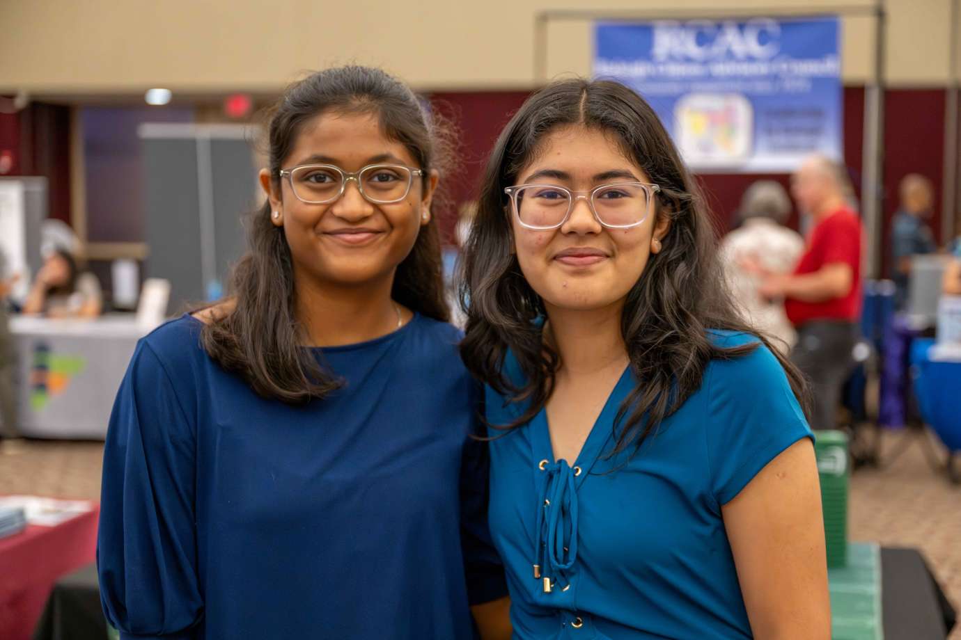Two girls stand side-by-side in the expo hall.