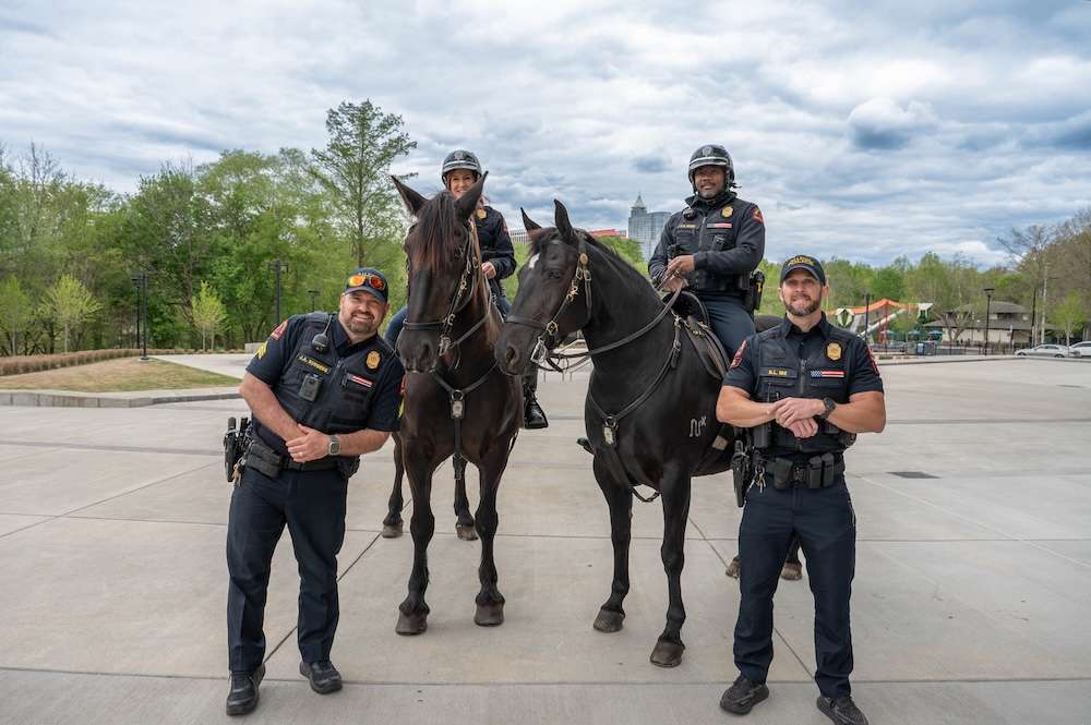 Four offciers, two of the mounted on horses, stand and pose