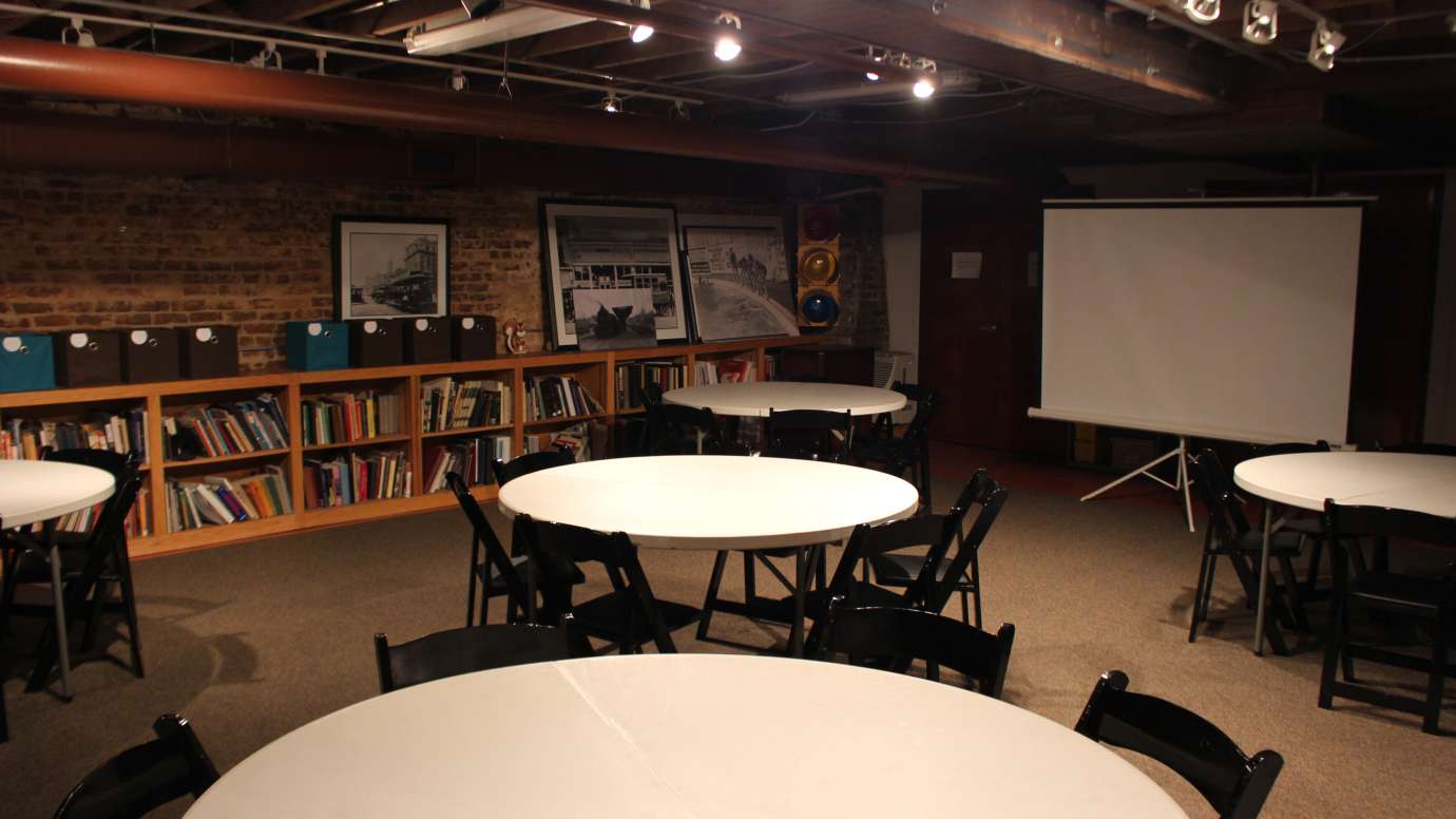 a meeting room with round tables and projector screen