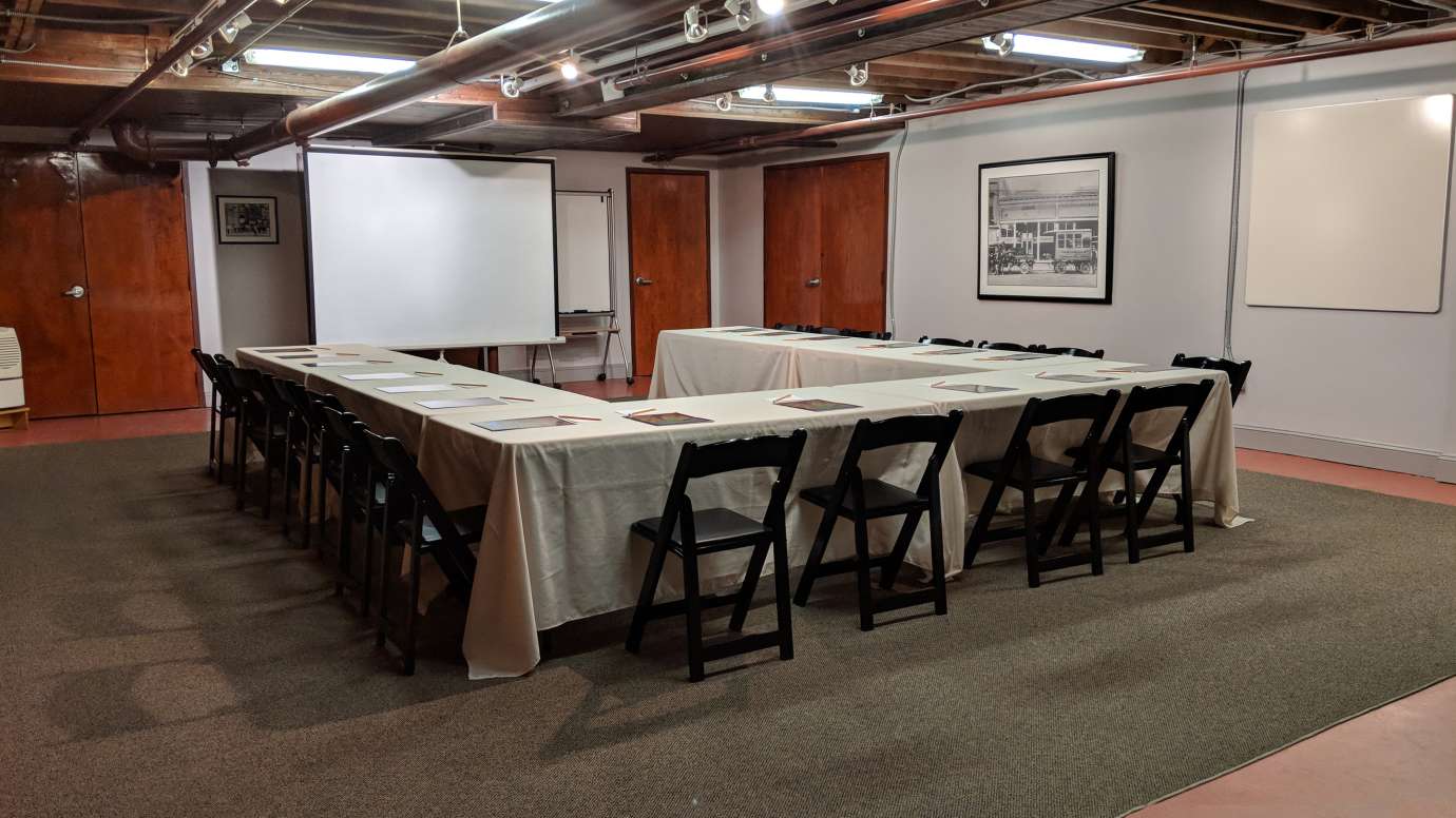 a meeting room with rectange tables and projector screen
