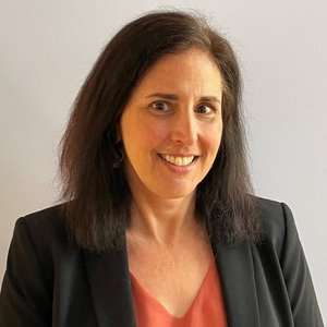 Headshot of Laura Wells wearing a dark blazer with a colored shirt