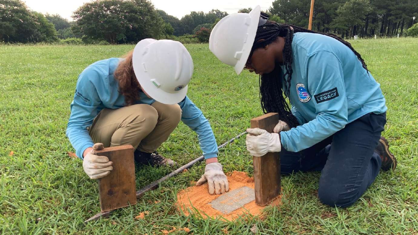 young adults helping raise a grave site