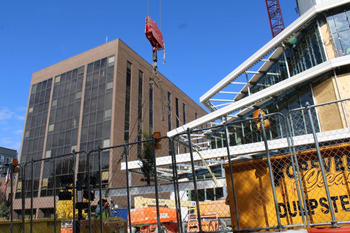 Image of topping out beam rising in the air. 