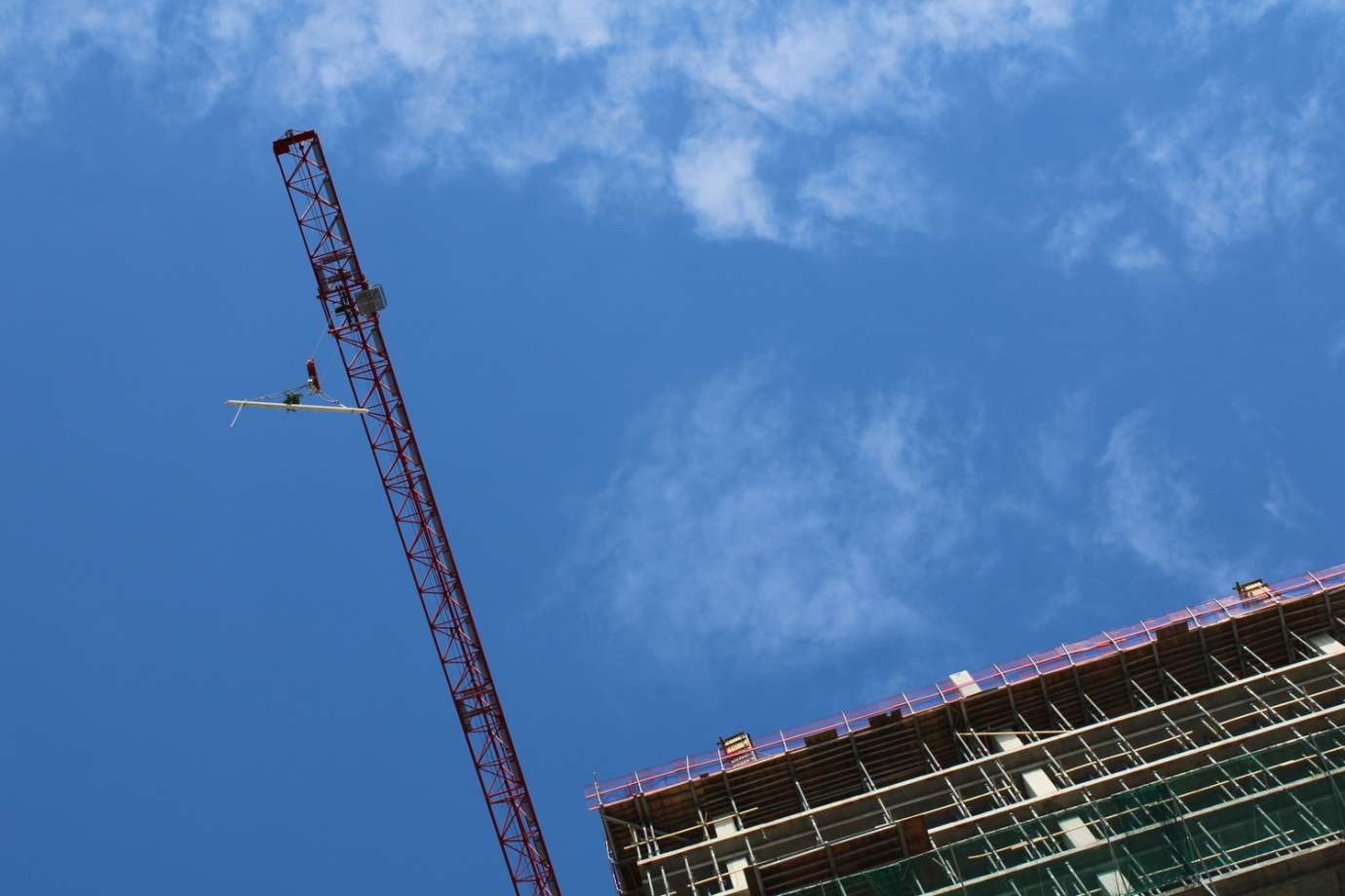 Image of topping out beam rising in the air. 