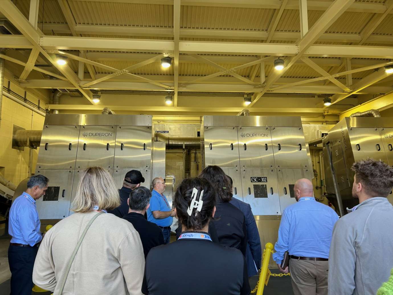 Group of people inside a building, listening to a tour guide.