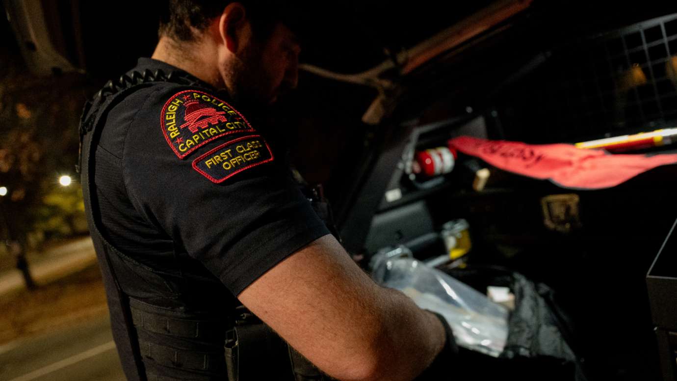 RPD officer reaches for bag in trunk of car