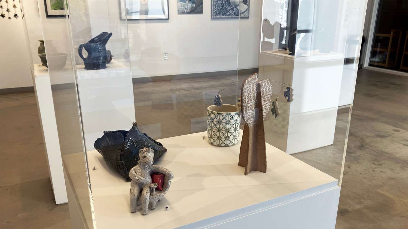 Display case of four works of pottery, including a small unicorn figure