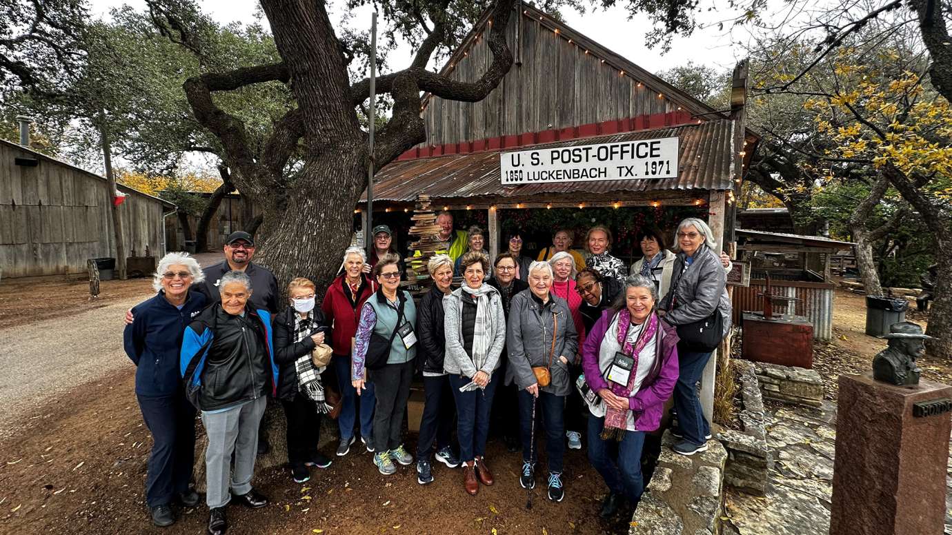 a group of adults on a trip smiling in front of an old building