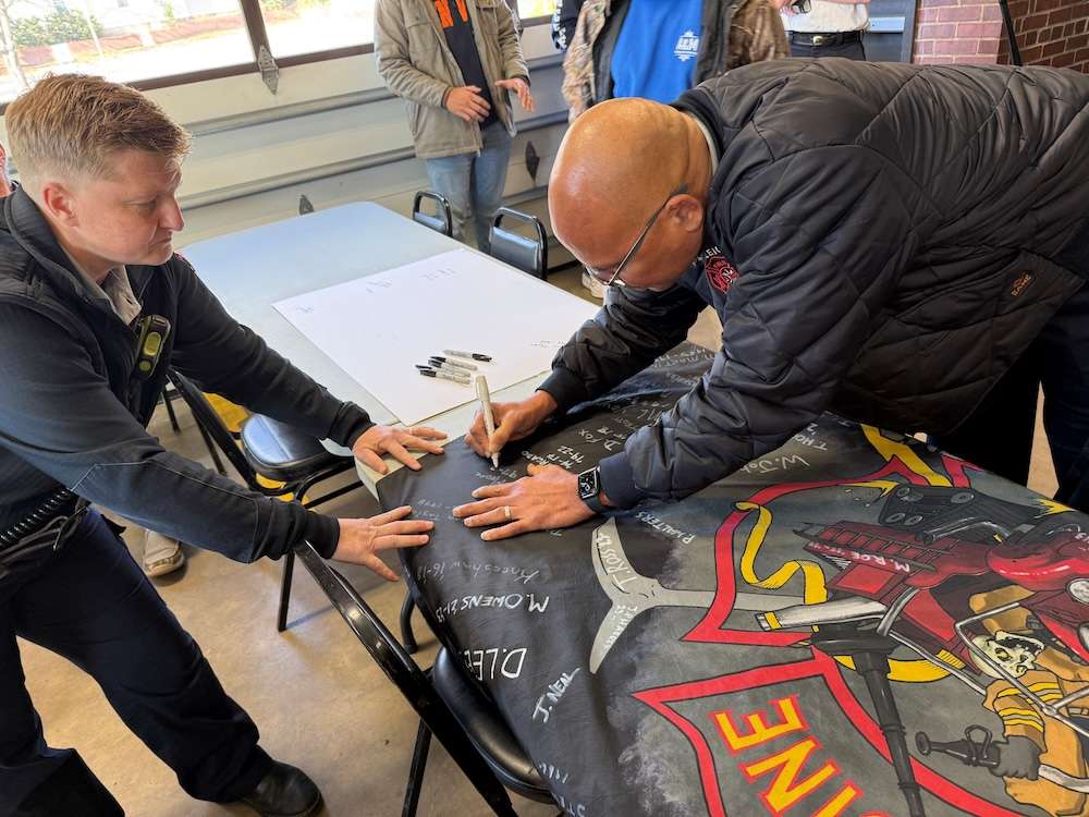 two men Signing the Fire Station 3 flag before the building closes in early 2026.