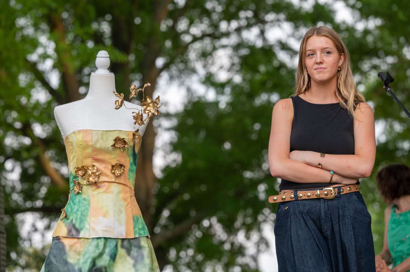 A woman poses with a mannequin wearing a dress made of recycled material. 