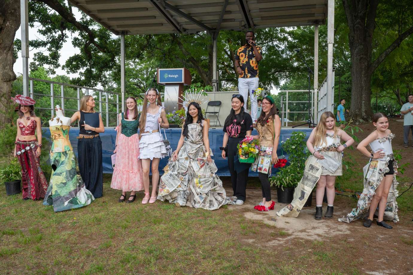 The finalists in the 2025 Trashion Show pose in front of the Dix Park Stage in their outfits made of recycled materials.