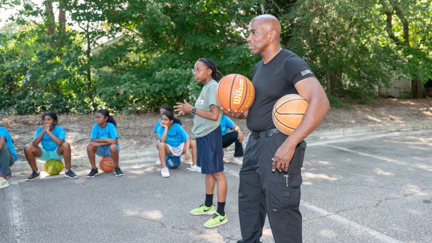 Police youth basketball coach holding two basketballs